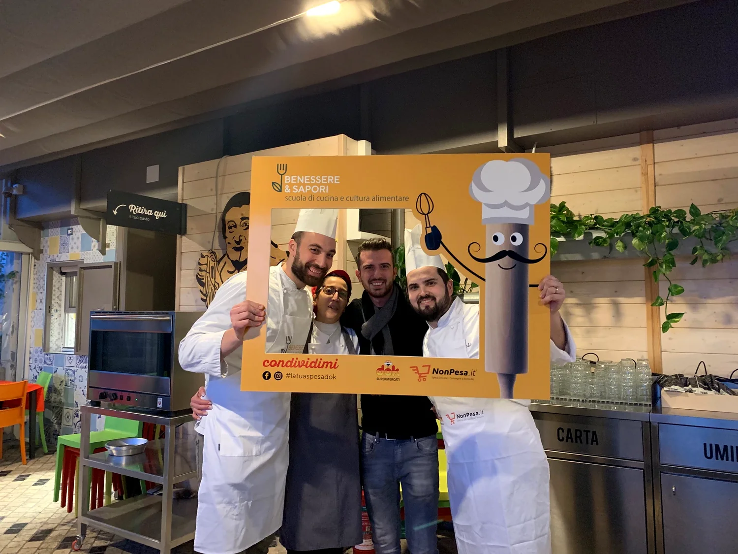 Partecipanti e cuochi sorridono insieme durante un corso di cucina Dok